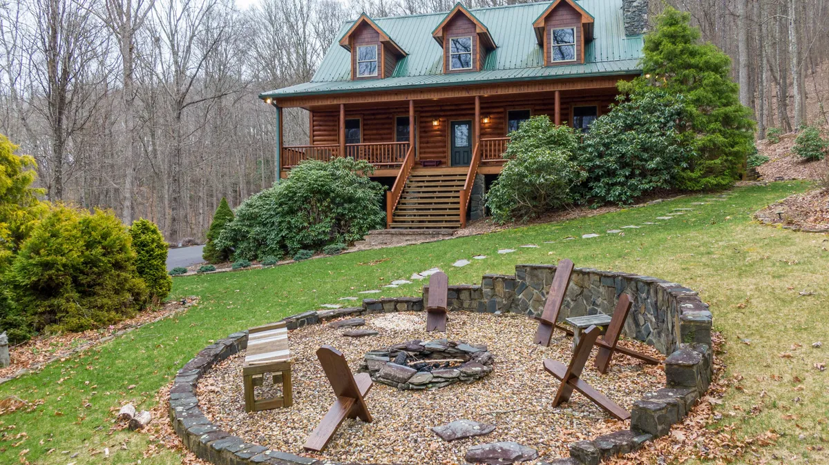 An exterior view features the log cabin, a welcoming fire pit surrounded by wooden chairs, and a landscaped garden. The image evokes scenes of group gatherings, evening fireside chats, barbecue sessions, and enjoying the outdoors.