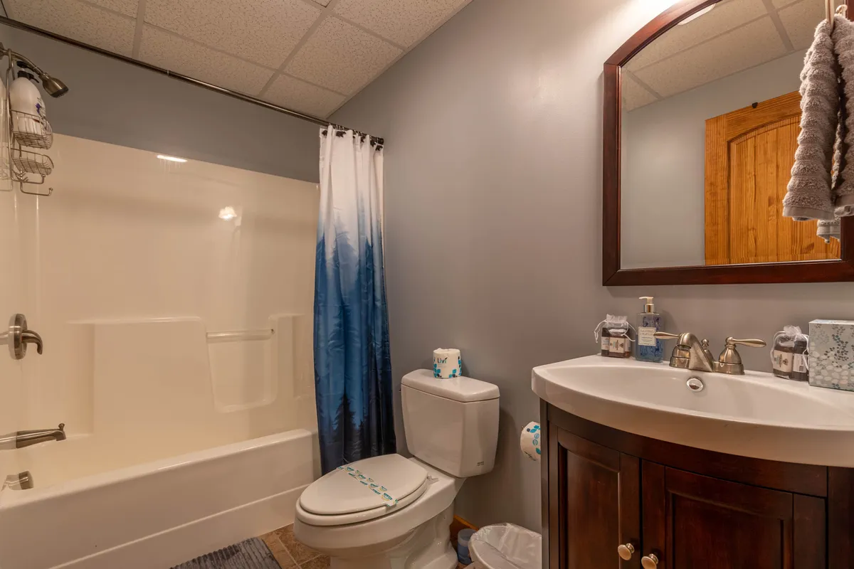 This image features a bright, tidy bathroom with a shower and curtain, a vanity sink, mirror, and toilet. The design is functional yet relaxing, suited for refreshing routines at any time of the day.